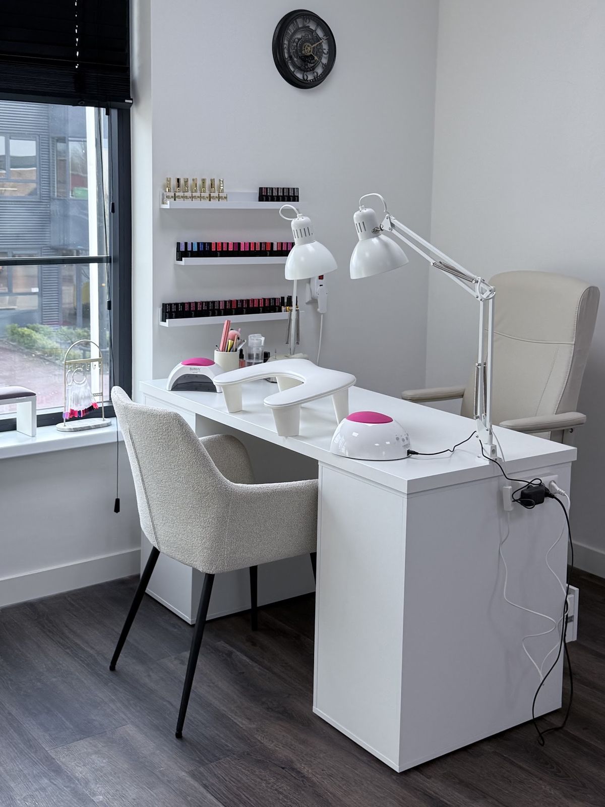 De witte manicuretafel bij het raam, met planken vol lak aan de muur