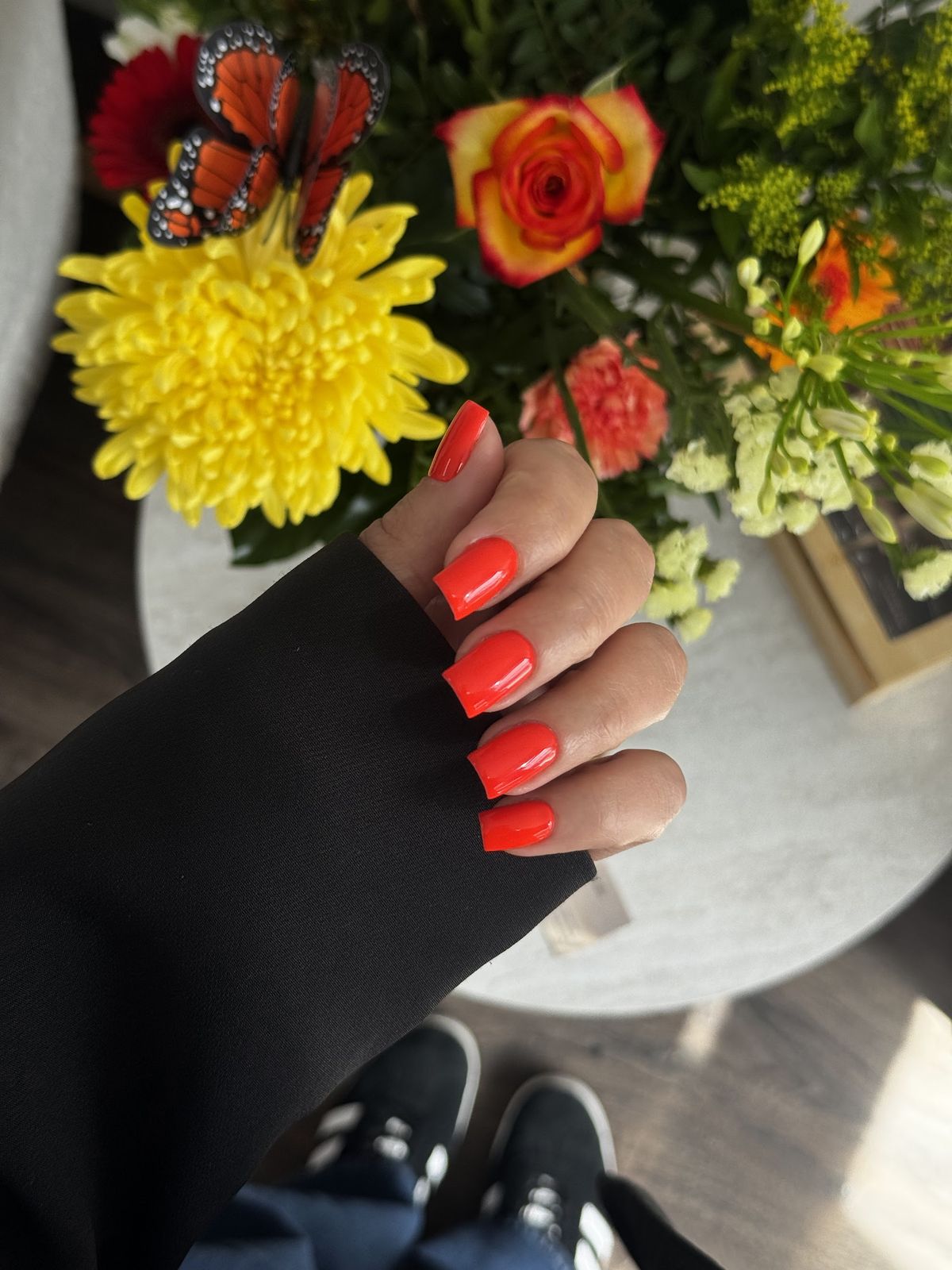 Felrode vierkante nagels naast een boeket met een vlinder