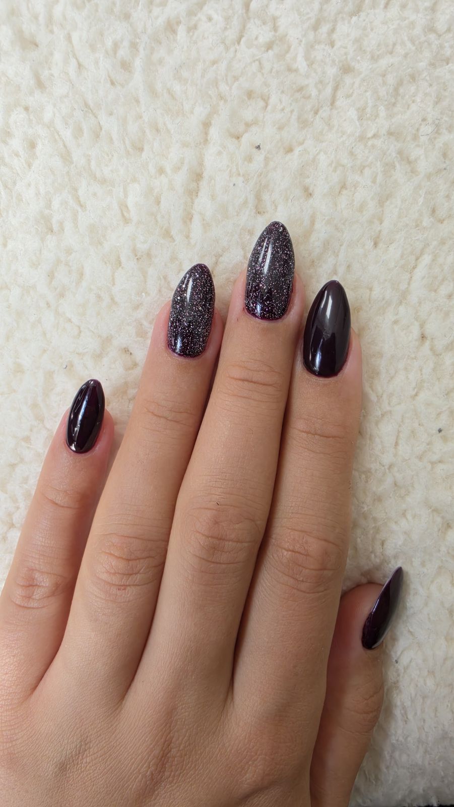 Aubergine nagels met glitter op een schapenvacht