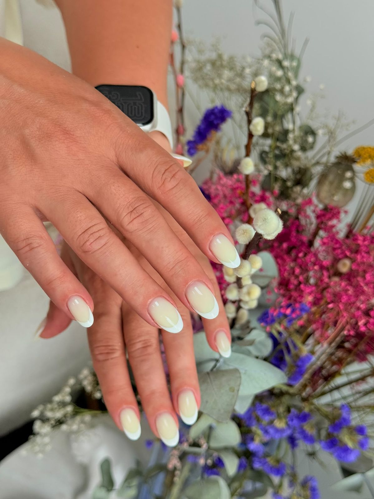 Klassieke French op ovale nagels, naast een boeket
